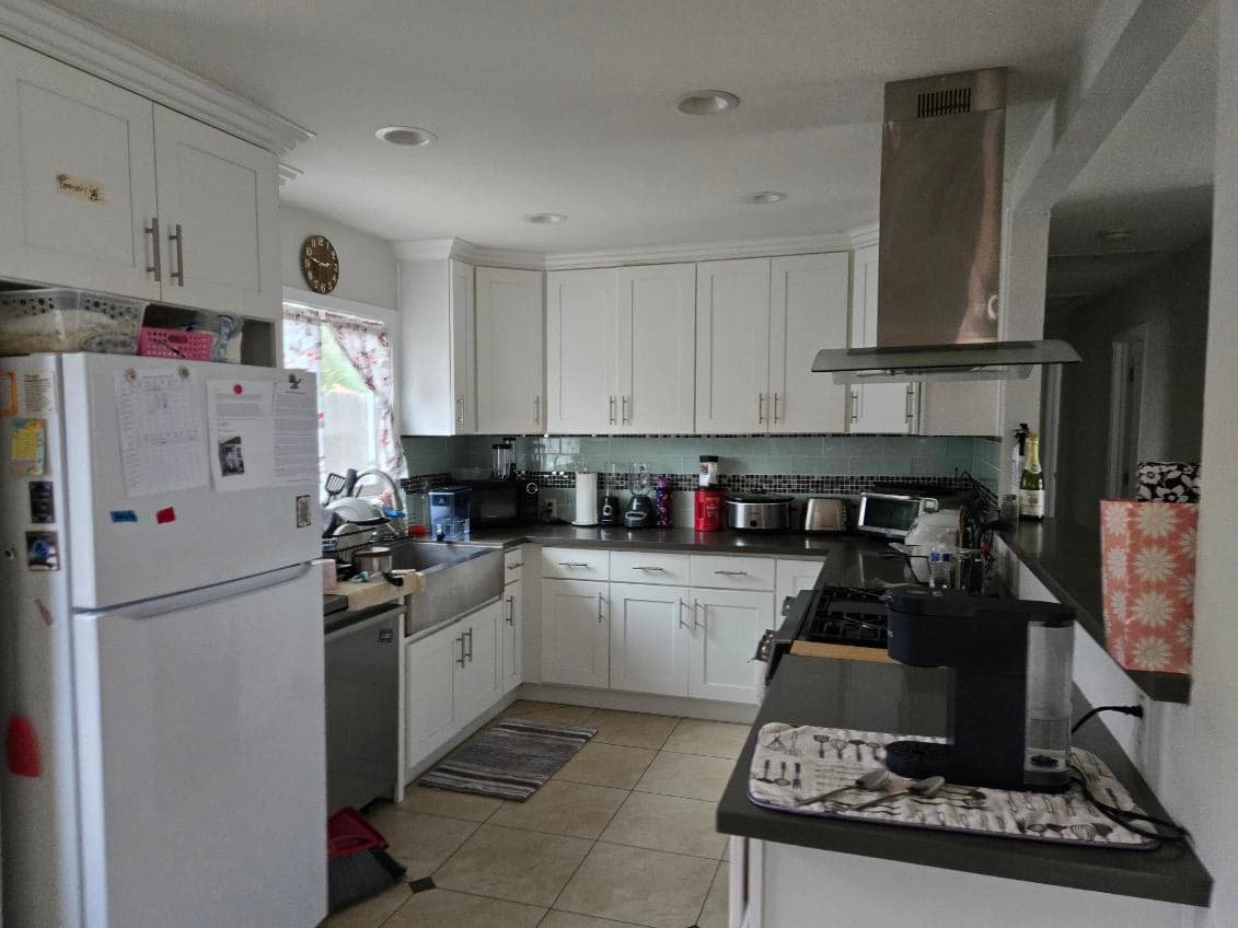 Agape House 3 kitchen — white cabinets, modern range hood, and tile backsplash